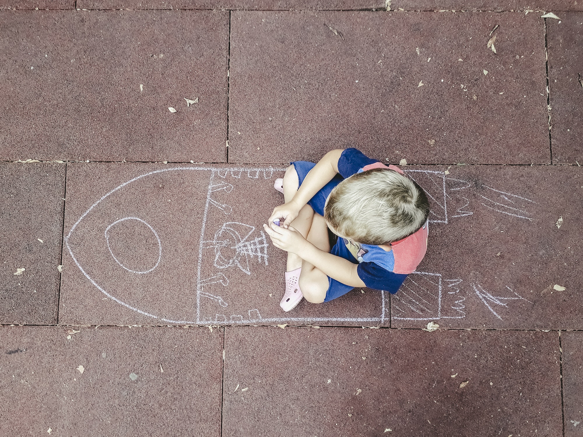 Happy child playing to imagine spaceships painted with chalk.