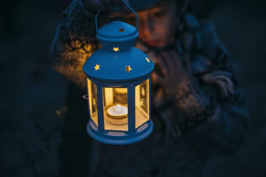 Italy, Grosseto, boy looking at a lighted Christmas lantern by night