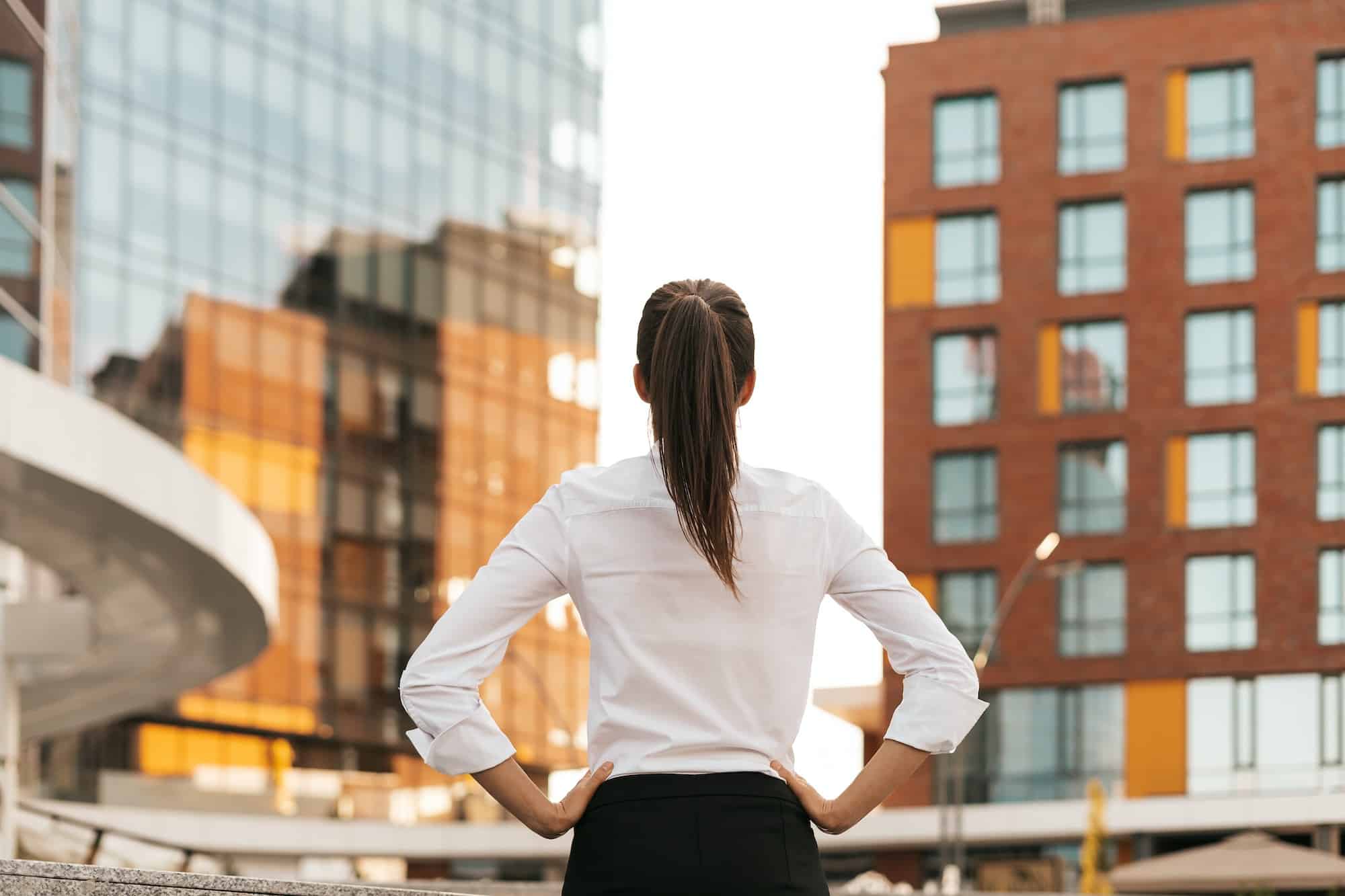 Rear view of woman looking across city business buildings