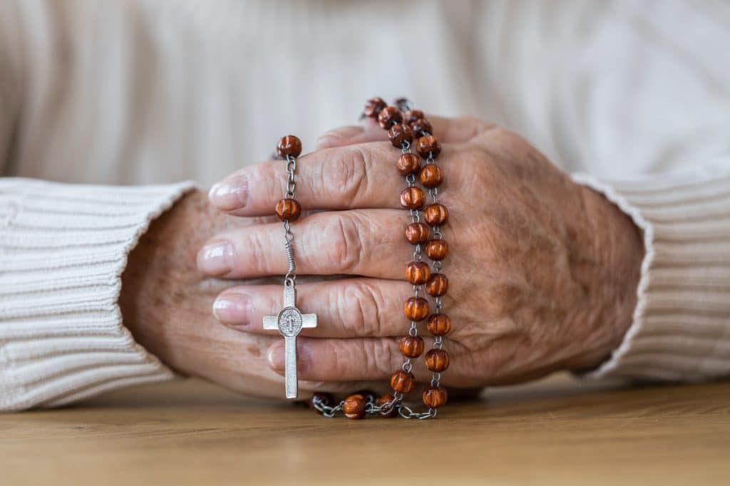 Senior's hands with red rosary