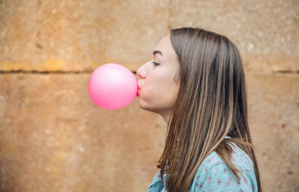 Young teenage girl blowing pink bubble gum